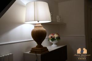 巴勒摩的住宿－BUTERA APARTMENTS LUXURY，花瓶旁边的桌子上的一盏灯