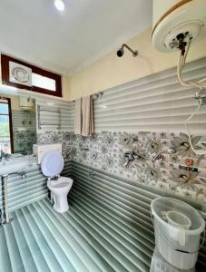 a bathroom with a toilet and a sink at Hotel Anuj Regency in Dharamshala