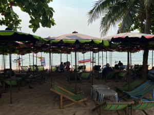 a group of chairs and umbrellas on a beach at Yuri Guesthouse in Jomtien Beach