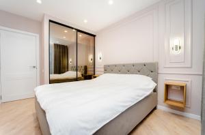 a white bedroom with a large bed and a mirror at 2BD Buiucani Urban Haven in Chişinău