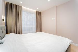 a bedroom with a white bed and a window at 2BD Buiucani Urban Haven in Chişinău