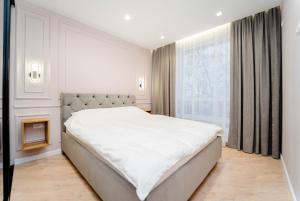 a white bedroom with a large bed and a window at 2BD Buiucani Urban Haven in Chişinău