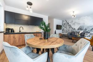 a kitchen and living room with a wooden table and chairs at Apartamenty Przełom Białki - plac zabaw, wiata grillowa in Białka Tatrzanska