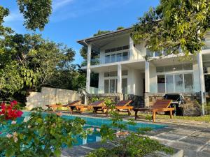 una casa con una piscina y mesas de picnic delante de ella en Samalanka Boutique Hotel, en Habaraduwa Central