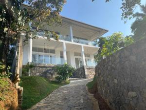 a large white house with a stone wall at Samalanka Boutique Hotel in Habaraduwa