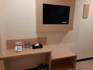 a room with a phone and a tv on a wall at Jakarta City Hotel in Jakarta +14 photos