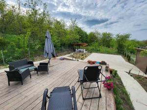 eine Holzterrasse mit Stühlen und einem Sonnenschirm in der Unterkunft Vila Elisa 