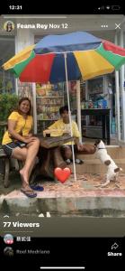 a man and a woman sitting on a bench under an umbrella at Anang Balay Turista in El Nido
