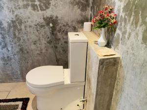 łazienka z toaletą i kwiatami na ladzie w obiekcie River Shadow Villa w mieście Bentota