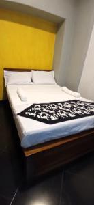 a bed with a black and white blanket on it at Yak City Apartments in Kandy