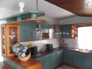 a kitchen with green cabinets and a vase of flowers at Hotel Gjika in Sarandë +37 photos