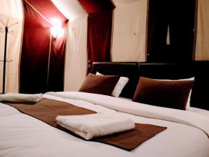 a bedroom with two beds with white sheets and brown pillows at Merzouga Wildlife Desert Camp in Merzouga