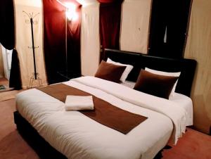 a bedroom with a large bed with brown and white sheets at Merzouga Wildlife Desert Camp in Merzouga