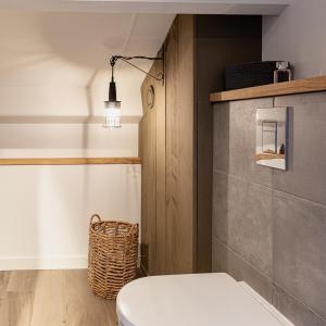 a bathroom with a toilet and a light on the wall at Huusje21 in Nunspeet