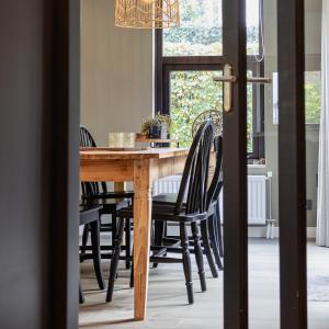 mesa de comedor con sillas negras y lámpara de araña en Huusje21, en Nunspeet