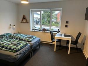Schlafzimmer mit einem Bett, einem Tisch und einem Fenster in der Unterkunft Ikast Bed & Kitchen in Ikast