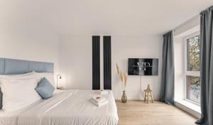 a white bedroom with a large bed and a window at Modernes Apartment am Gleispark in Oldenburg