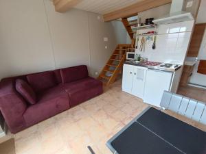 a living room with a purple couch and a kitchen at La coco's house in Planchez