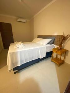 a bedroom with a white bed with a night stand at Pousada Vibe Guajiru in Trairi