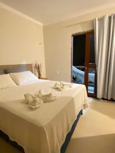 a bedroom with a bed with white sheets and a window at Pousada Vibe Guajiru in Trairi