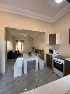 Il comprend une cuisine et un salon avec une table blanche. dans l'établissement KMR Apartment - Kumba, à Serekunda