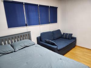 a bedroom with a bed and a blue couch at Spacious Master Suite in Seoul