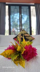 a bouquet of flowers on a table with a window at NeemTree Villa- 5 Bedroom House On Its Own in Nadi