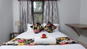 a bedroom with a bed with a flower patterned pillow at NeemTree Villa- 5 Bedroom House On Its Own in Nadi