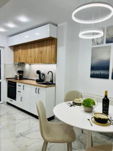 a white kitchen with a white table and chairs at MarbleHome~Straja/Lupeni in Lupeni