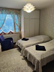 1 Schlafzimmer mit 2 Betten, einem Stuhl und einem Kronleuchter in der Unterkunft City Home Lahti in Lahti