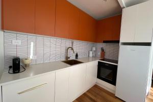 a kitchen with white cabinets and an orange wall at PIPI SHACK - iconic waterfront shack Binalong Bay in Binalong Bay