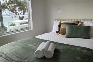 a bedroom with a bed with rolled towels on it at PIPI SHACK - iconic waterfront shack Binalong Bay in Binalong Bay