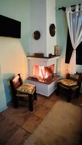 - un salon avec une cheminée et 2 chaises dans l'établissement Guesthouse Filokalia, à Portariá