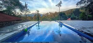 a swimming pool with blue water and mountains in the background at Green Garden Lotus Villa in Wayanad