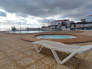 a white bench sitting in front of a swimming pool at Casa Yanira in Caleta De Fuste