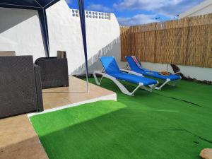 un patio con 2 sillas y una alfombra verde en Casa Yanira, en Caleta de Fuste