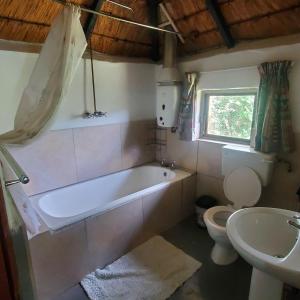 a bathroom with a tub and a toilet and a sink at Mashai Rest Rondavel in Underberg