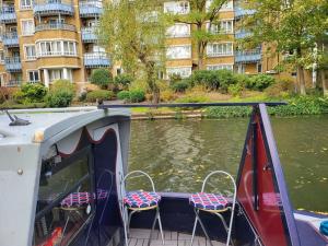 a boat with chairs on the side of a river at Comfy Canal Boat in London Centre Family & Friends in London