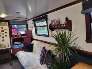 a living room with a couch and a plant at Comfy Canal Boat in London Centre Family & Friends in London