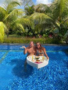 a man and woman sitting in a table in a swimming pool at The Jiwana Bali Resort in Ungasan