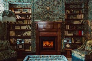 a living room with a fireplace and bookshelves at Hôtel Eldorado Paris in Paris