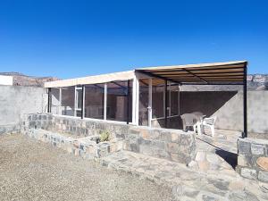 a house with a stone wall and a table and chairs at Stone rest house jebel shams in Al Ḩamrāʼ