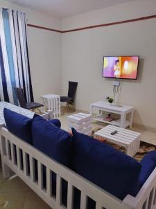 sala de estar con sofá azul y TV en Cozy Nyumbani Studio Apartment In Mtwapa ., en Mtwapa
