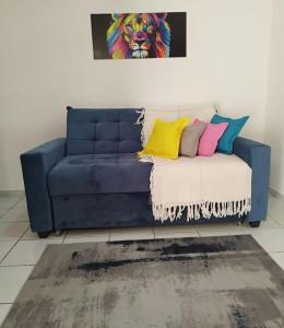 een blauwe bank met kleurrijke kussens in de woonkamer bij Ótimo apartamento em Ponta Negra in Natal