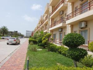 a building with bushes and a car parked next to a street at Pearl Suites at Omaxe Eternity in Vrindāvan