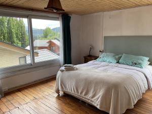 1 dormitorio con cama y ventana grande en Casa Balmaceda Backpackers, en Coyhaique