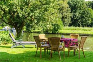 een tafel en stoelen in het gras bij een meer bij Historical house on river Vecht in Maarssen