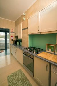 uma cozinha com armários brancos e um forno com placa de fogão em The Terrace em Ponta Delgada