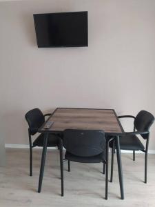 a wooden table with chairs and a television on a wall at Haus Kellerwald - Ferienwohnung Kellerwald-Edersee in Jesberg +41 photos