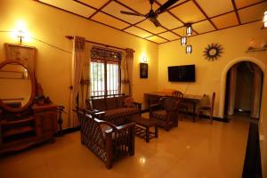 a living room with a table and chairs and a television at Serene villa in Galle
